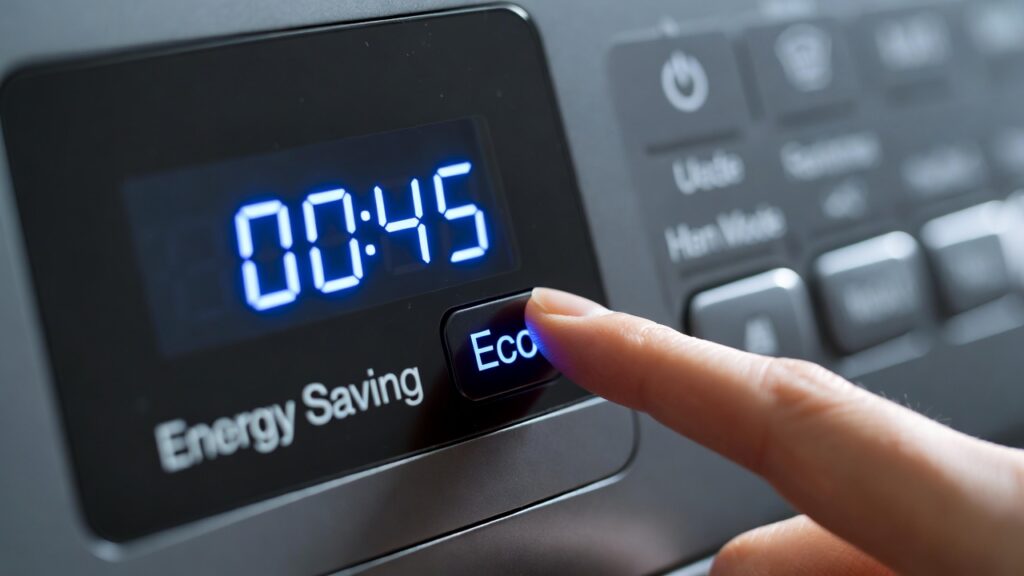 Close-up of a finger pressing a glowing Eco button on a washing machine control panel with Energy Saving Mode display.

